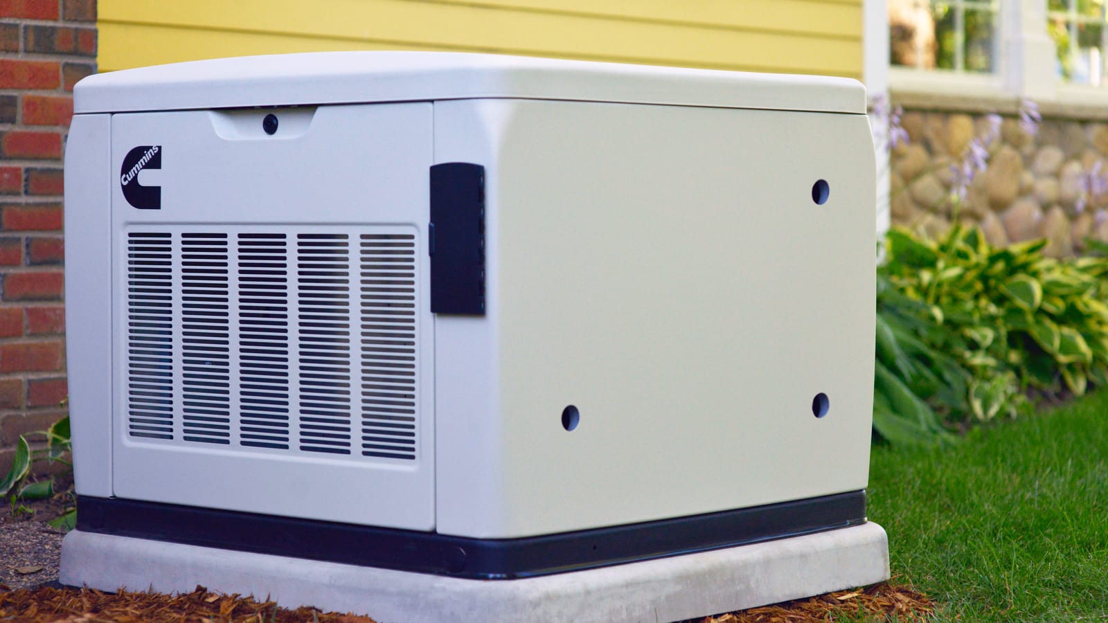 Cummins air-cooled home standby generator on a concrete pad beside a house